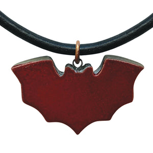 Deep red bat-shaped pendant on a black cord against a white background