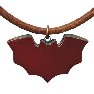 Deep red bat-shaped pendant on a brown cord against a white background