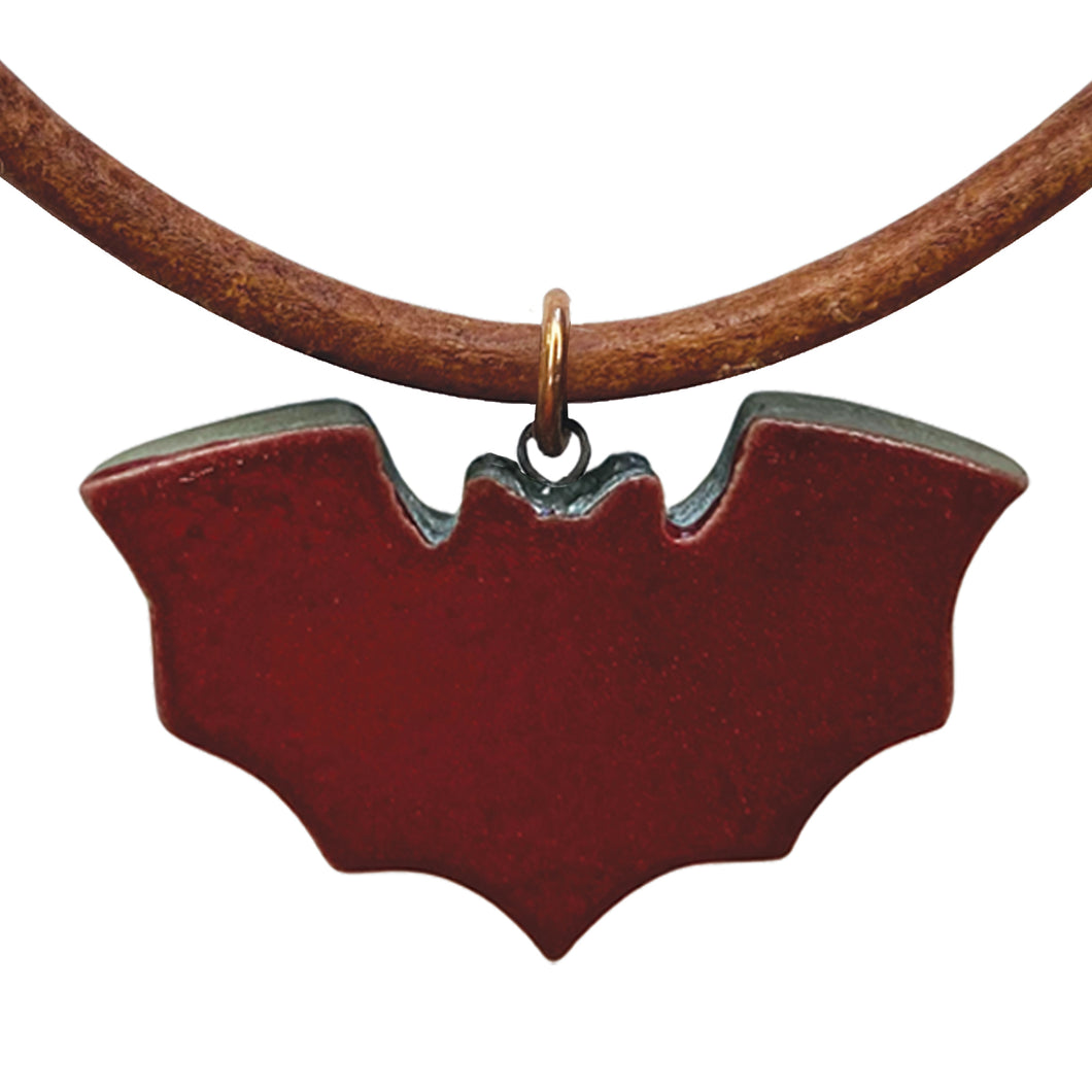 Deep red bat-shaped pendant on a brown cord against a white background