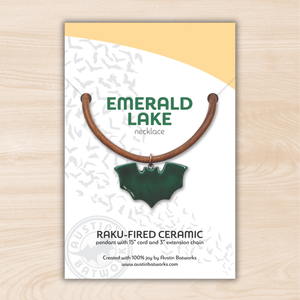 Emerald Lake necklace packaging with green ceramic pendant on a wooden surface