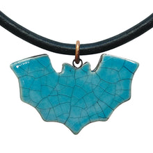Turquoise bat-shaped pendant on a black cord against a white background