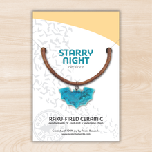 Starry Night necklace packaging with blue ceramic pendant on a light wood background
