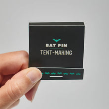 Left hand holding matchbox-style packaging with black front