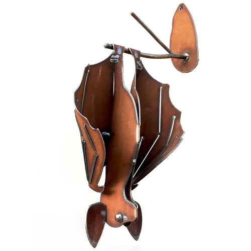 Left hanging cinnamon-rusted metal bat sculpture with open wings